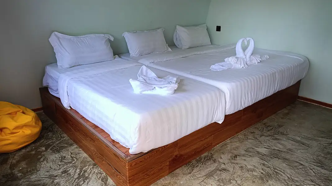 A comfortable deluxe room at Asia Rainforest Resort over the Celebes Sea featuring two large beds, modern style wooden platform, smooth concrete floors, and AC