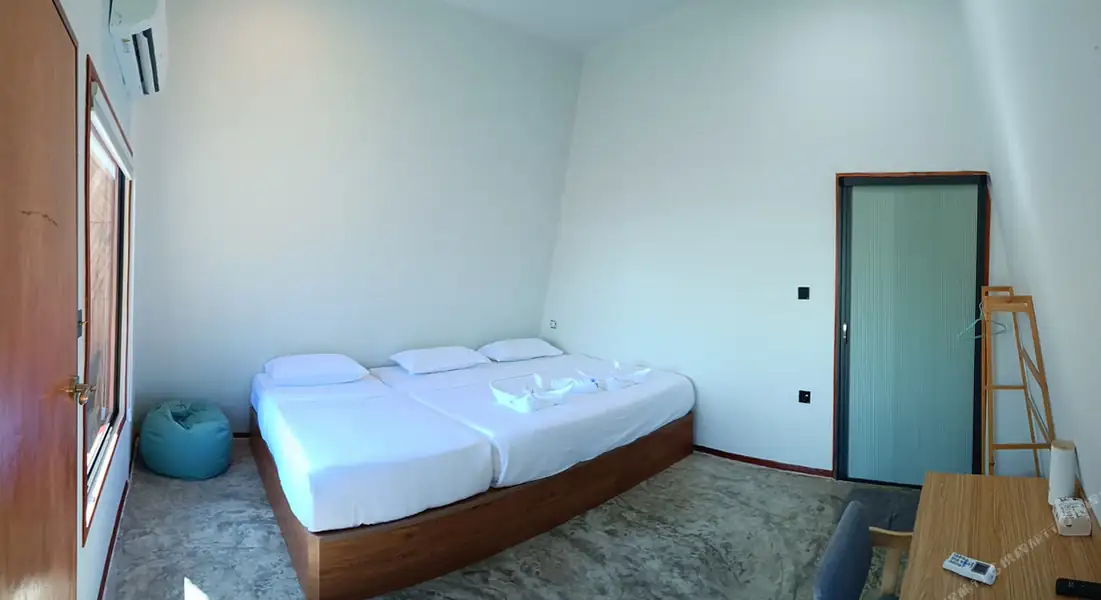A minimalist deluxe room at Asia Rainforest Resort in the Semporna archipelago featuring two large beds, modern style decor, smooth concrete floors, and air con