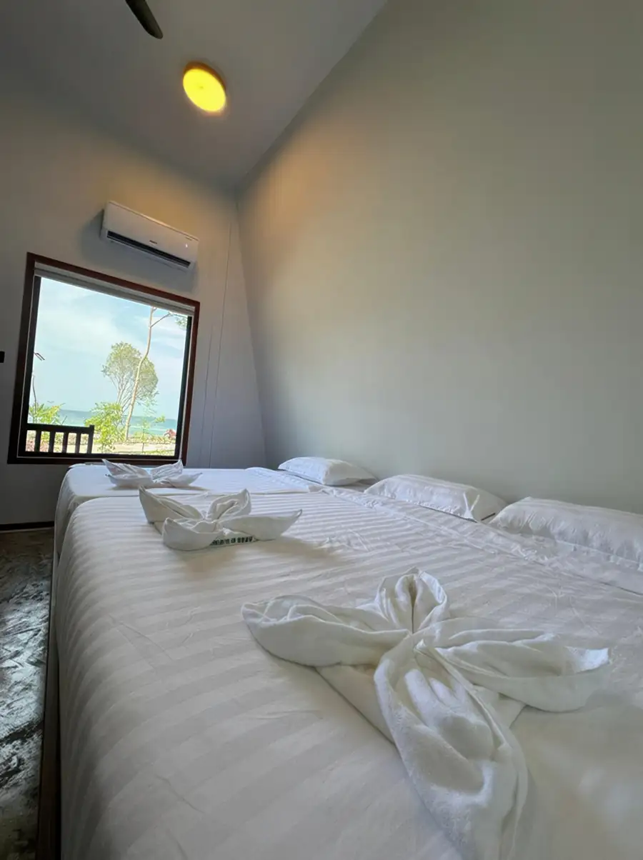 A tranquil deluxe bedroom at Asia Rainforest Resort near Tun Sakaran Marine Park featuring two large beds, modern style decor, polished concrete floors, AC, and a window framing the seaview
